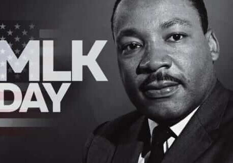 Black and white photo of Martin Luther King Jr. with “MLK DAY” text and an American flag background on the left side of the image.