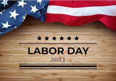 An American flag draped over a wooden surface with the text “LABOR DAY 2021” and decorative stars and lines below.
