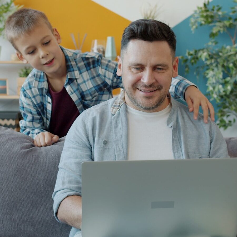 Father and son looking at laptop on couch
